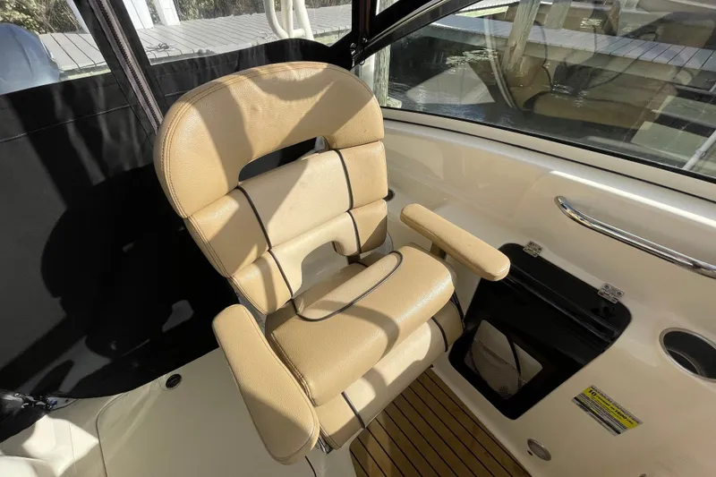 Slide: The Image of Captain's chair on 2015 Scout 245 Dorado boat, featuring beige upholstery and armrests. - 29