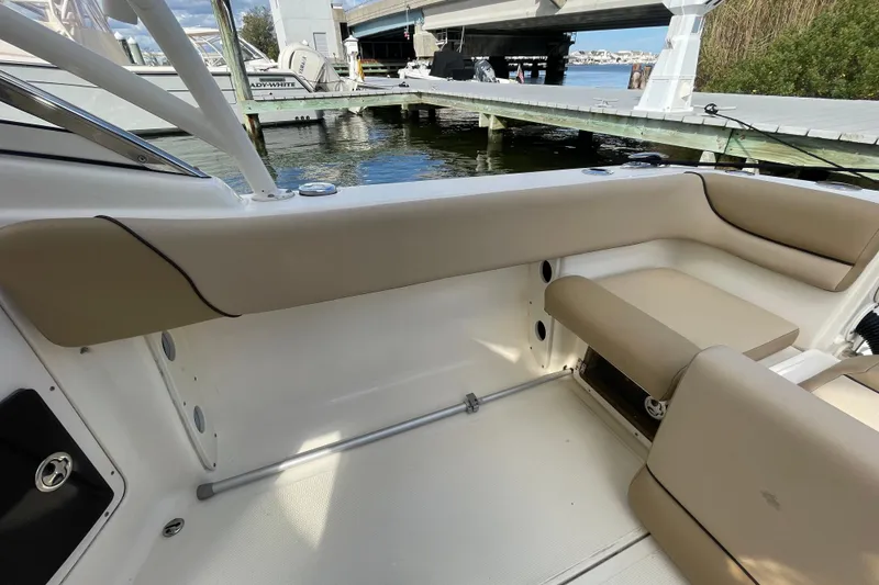 Slide: The Image of Interior view of a 2015 Scout 245 Dorado boat, featuring beige seating and a waterfront backdrop. - 35