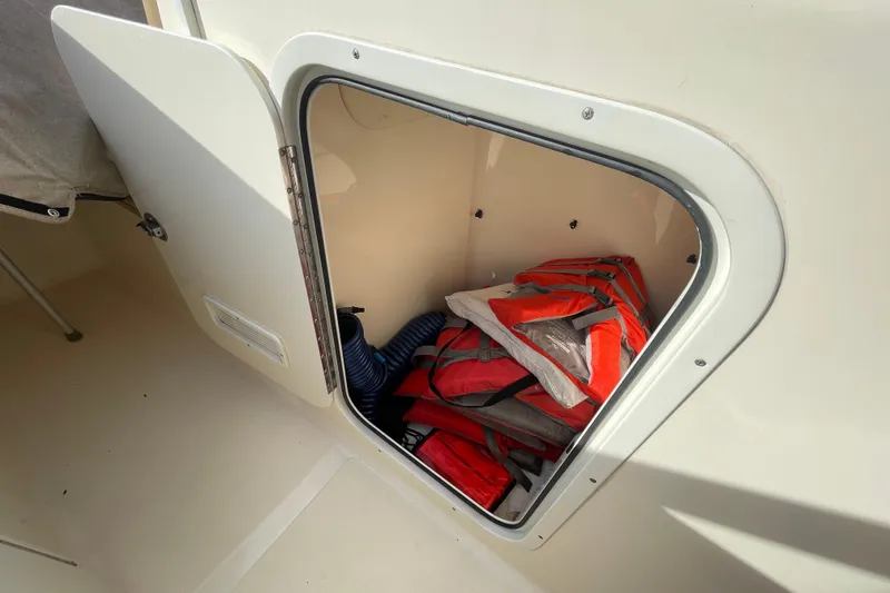 Slide: The Image of Open storage compartment on 2015 Scout 245 Dorado boat with life jackets inside. - 41