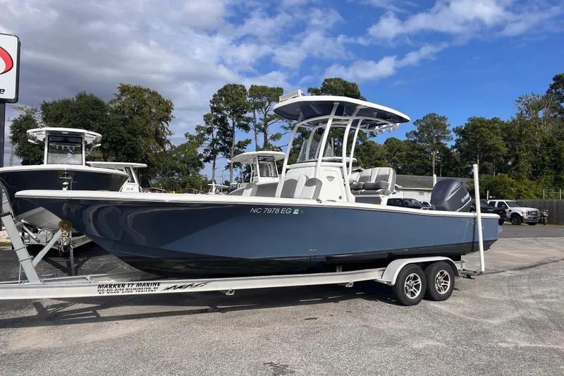 Slide: The Image of 2017 Tidewater 2500 Carolina Bay boat on trailer, parked outdoors under a cloudy sky. - 2