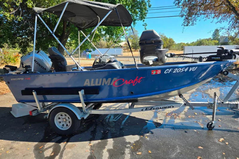 The Image of 2022 Alumacraft Escape 145 CS boat on trailer with canopy and Honda motor. - 1