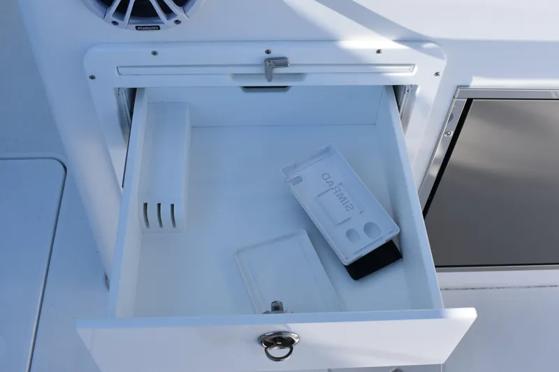 Slide: The Image of Open storage compartment on 2025 NauticStar 332 Offshore boat with SIMRAD device. - 38