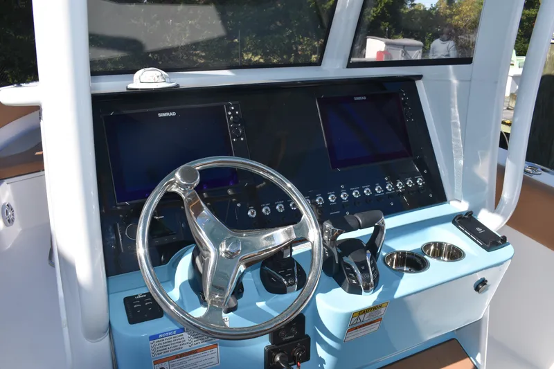 Slide: The Image of 2025 NauticStar 332 Offshore boat helm with dual Simrad displays and stainless steel steering wheel. - 47