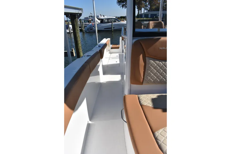 Slide: The Image of 2025 NauticStar 332 Offshore boat interior with tan seating, docked at marina. - 83