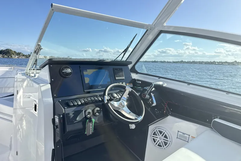 Slide: The Image of 2025 Blackfin 272 DC boat dashboard with navigation screen and controls, overlooking water. - 35