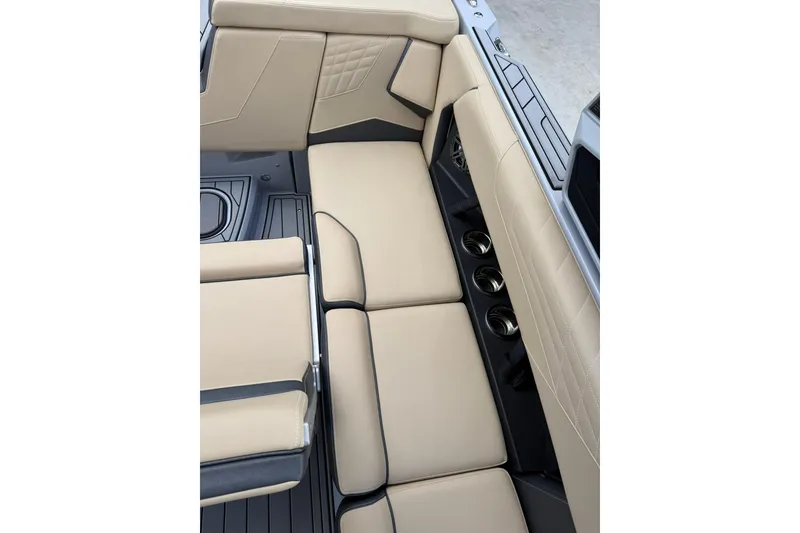 Slide: The Image of 2024 Nautique Super Air Nautique S23 interior seating with beige upholstery and cup holders. - 13