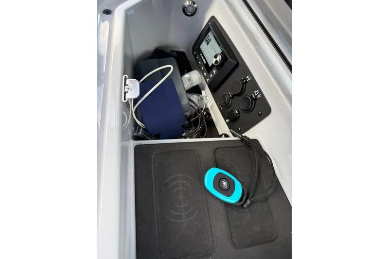 Slide: The Image of 2024 Nautique Super Air Nautique S23 storage compartment with control panel and accessories. - 6