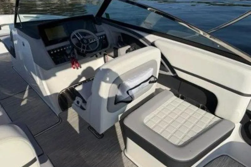 Slide: The Image of 2024 Cobalt R30 boat interior with steering wheel and seating, on calm water. - 7