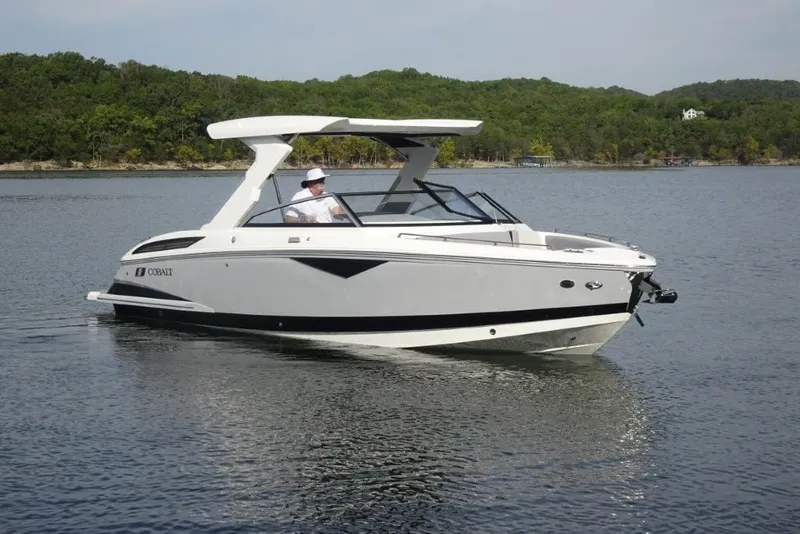 The Image of 2026 Cobalt A29 boat cruising on a serene lake with lush green shoreline. - 0