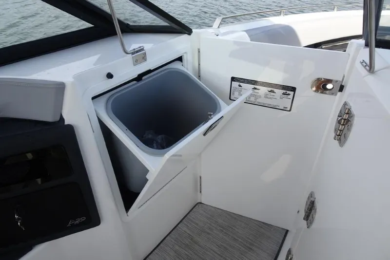Slide: The Image of 2026 Cobalt A29 boat interior with open storage compartment and trash bin. - 19