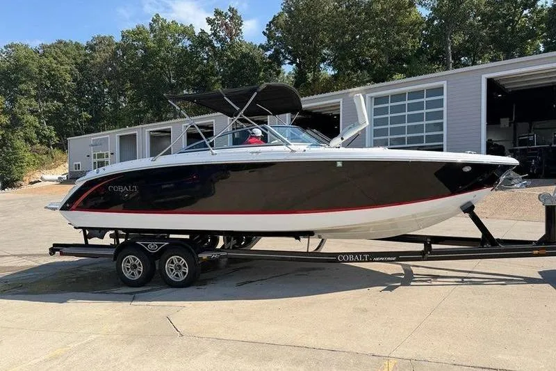 Slide: The Image of 2015 Cobalt R7 boat on trailer, black and white design, parked near garages. - 2