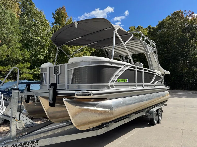 The Image of 2023 Godfrey Monaco 255 SD pontoon boat on trailer, parked outdoors under blue sky. - 1