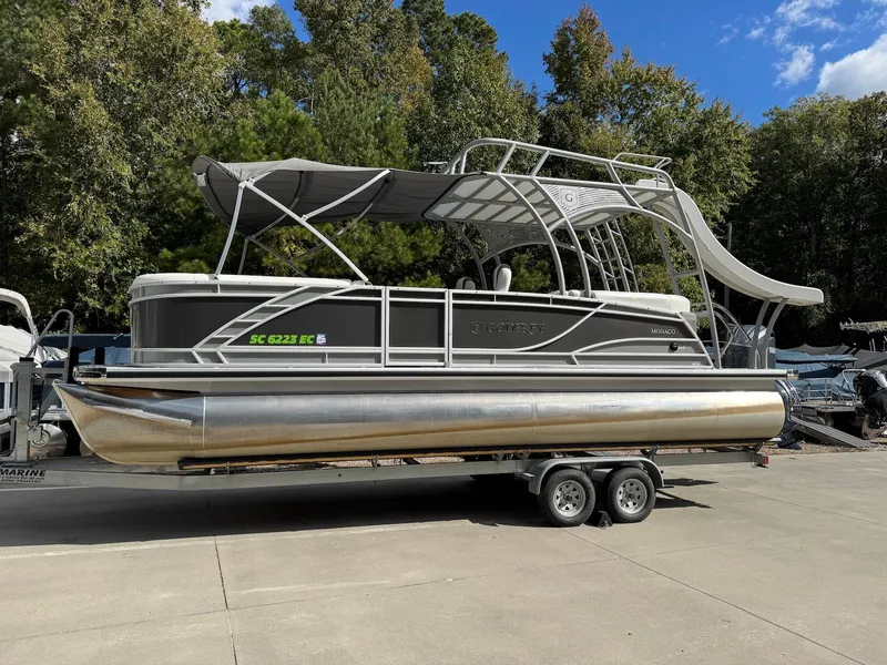 Slide: The Image of 2023 Godfrey Monaco 255 SD pontoon boat on trailer, parked outdoors. - 2