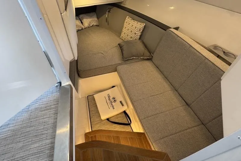 Slide: The Image of 2024 Cobalt R35 interior cabin with gray seating, cushions, and a tote bag. - 17