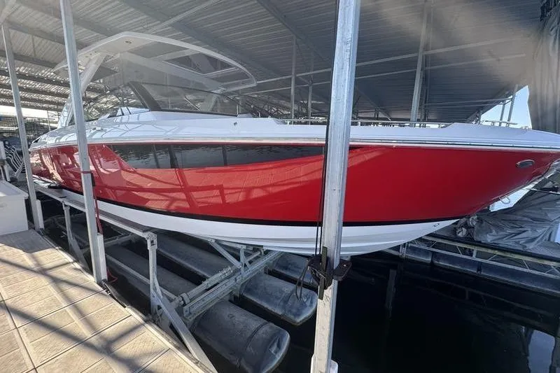 Slide: The Image of 2024 Cobalt R35 boat in red and white, docked under a covered marina. - 2
