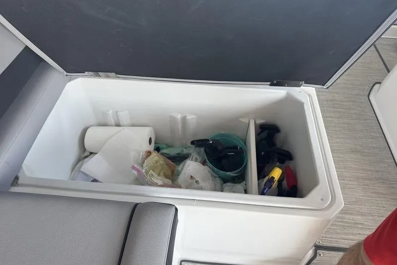 Slide: The Image of Open storage compartment in 2024 Cobalt R35 boat with cleaning supplies and paper towels. - 22