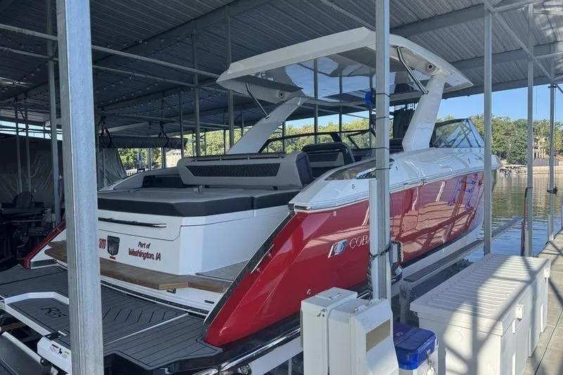 Slide: The Image of 2024 Cobalt R35 boat docked under a covered marina, featuring sleek red and white design. - 5
