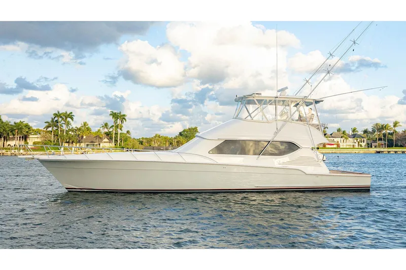 The Image of 2012 Bertram 60 yacht on water, with palm trees and cloudy sky in background. - 0