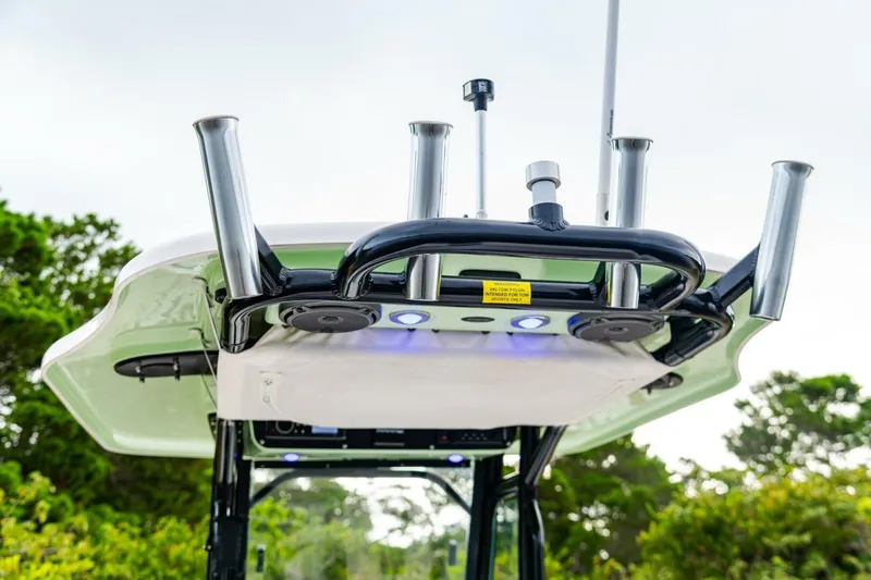 Slide: The Image of 2018 Everglades 243 Center Console boat with rod holders and canopy, set against a natural backdrop. - 23