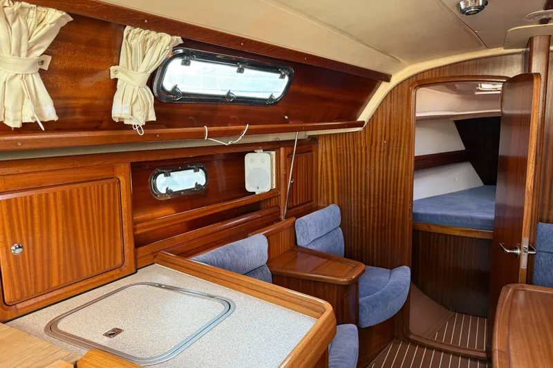 Slide: The Image of Interior of 2002 Bavaria 37 Sloop, featuring wood paneling and cozy seating area. - 18