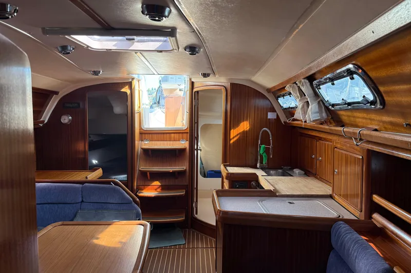 Slide: The Image of Interior of 2002 Bavaria 37 Sloop, featuring wood cabinetry and seating area. - 22