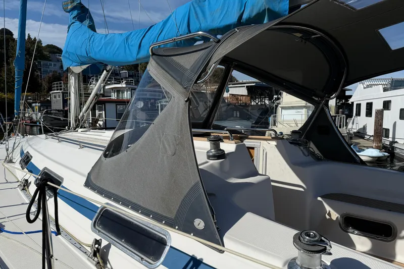 Slide: The Image of 2002 Bavaria 37 Sloop sailboat docked, featuring blue sail cover and cockpit canopy. - 26
