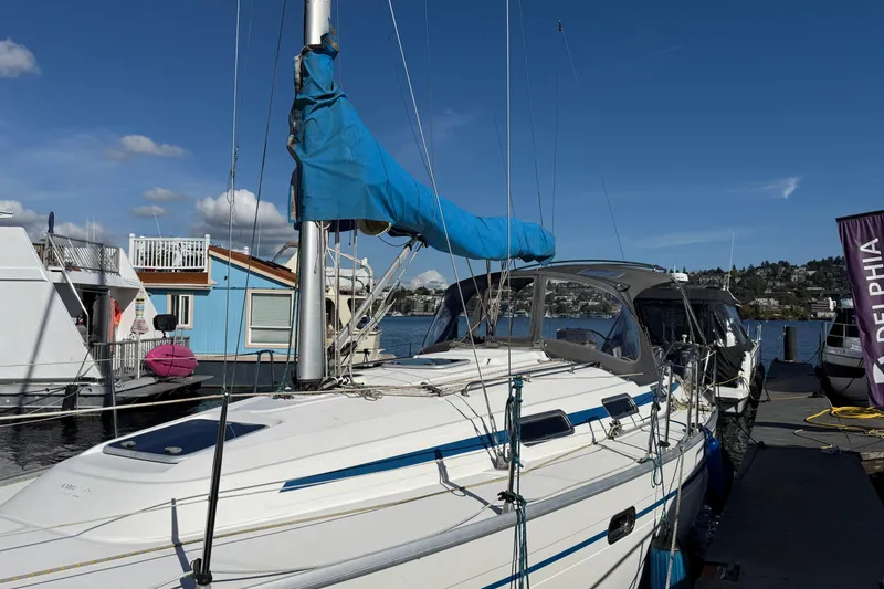 Slide: The Image of 2002 Bavaria 37 Sloop docked, blue sail cover, sunny day, waterfront view. - 27