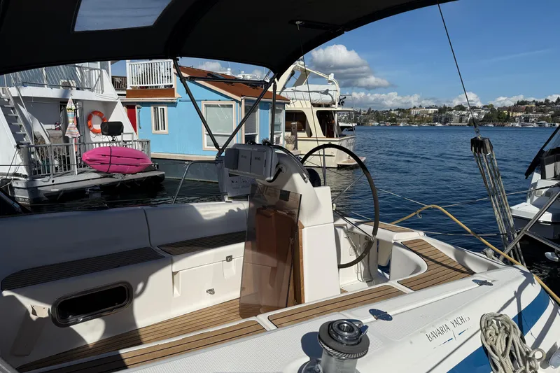 Slide: The Image of Bavaria 37 Sloop, 2002 model, docked near colorful houseboats on a sunny day. - 8