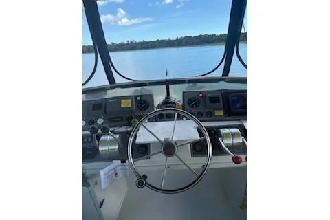 Slide: The Image of 1990 Californian 45 Motor Yacht helm with steering wheel and controls, overlooking calm waters. - 18