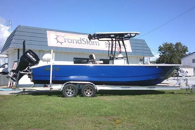 Slide: The Image of 2023 Carolina Skiff 26 Ultra Elite boat on trailer, blue hull, parked outside dealership. - 1