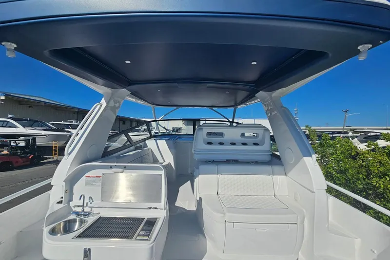 Slide: The Image of 2026 Intrepid 438 Evolution boat interior with seating and kitchenette under a blue canopy. - 4