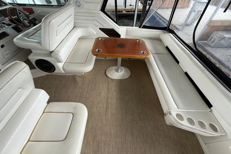 Slide: The Image of 1997 Sea Ray 400 Express Cruiser interior with white seating and wooden table. - 12