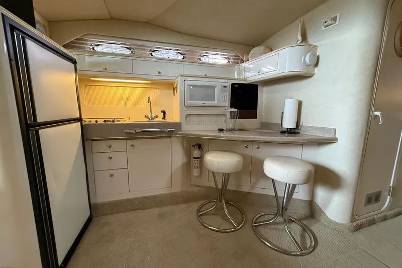 Slide: The Image of Interior of 1997 Sea Ray 400 Express Cruiser with kitchenette and bar stools. - 23
