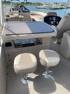 Slide: The Image of 2022 Avalon Catalina Entertainer boat interior with seating and table, docked by the water. - 16