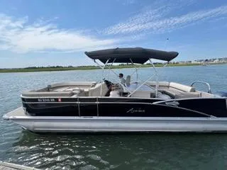 Slide: The Image of 2022 Avalon Catalina Entertainer 24' pontoon boat on calm water, blue sky background. - 23