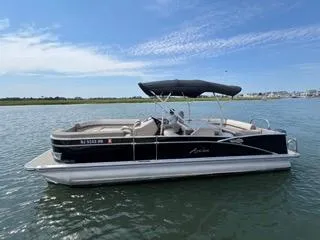 Slide: The Image of 2022 Avalon Catalina Entertainer 24' pontoon boat on calm water under blue sky. - 24