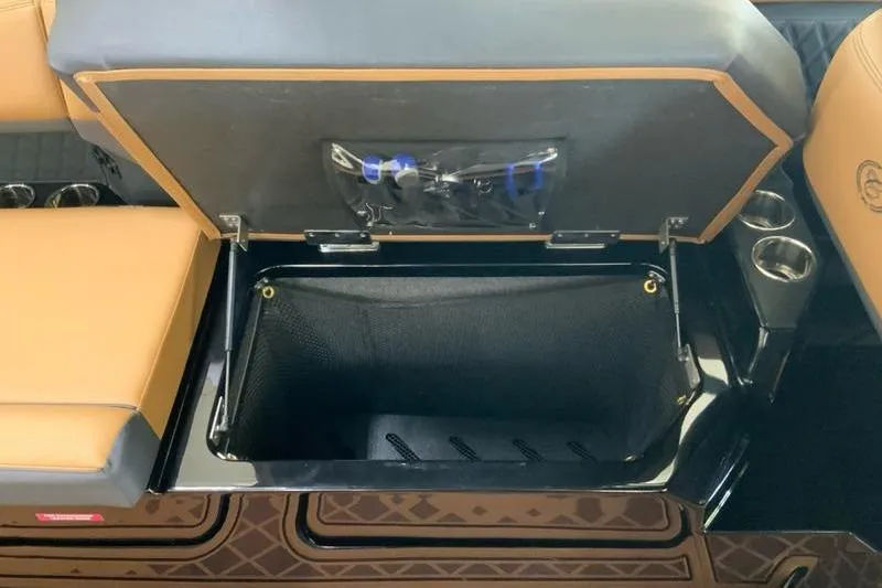 Slide: The Image of Open storage compartment in 2026 Cobalt R31 Surf boat with cup holders and cushioned seating. - 27