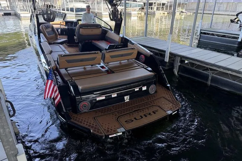 Slide: The Image of 2026 Cobalt R31 Surf boat docked, featuring spacious seating and American flag. - 6