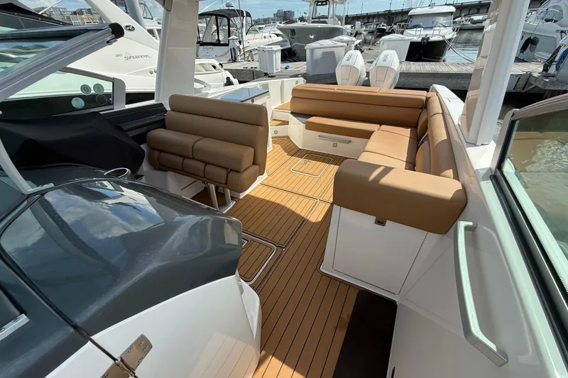 Slide: The Image of 2022 Aviara AV32 OB boat interior with tan seating and teak flooring at a marina. - 8
