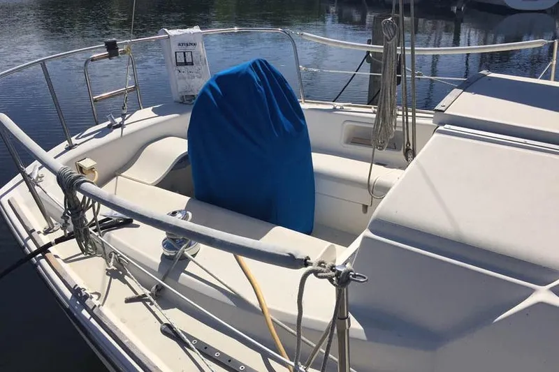 Slide: The Image of 1983 Pearson 303 sailboat cockpit with blue-covered helm, docked on calm water. - 11