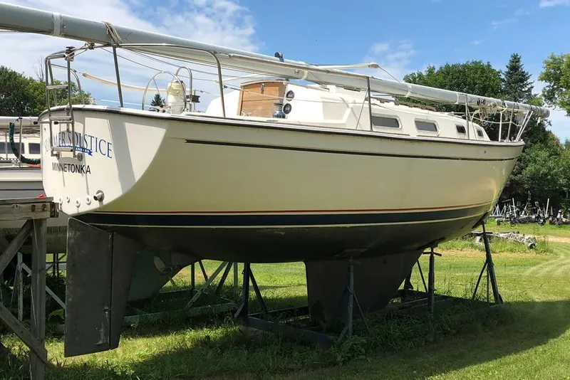 Slide: The Image of 1983 Pearson 303 sailboat on stands, displayed outdoors on grass. - 2