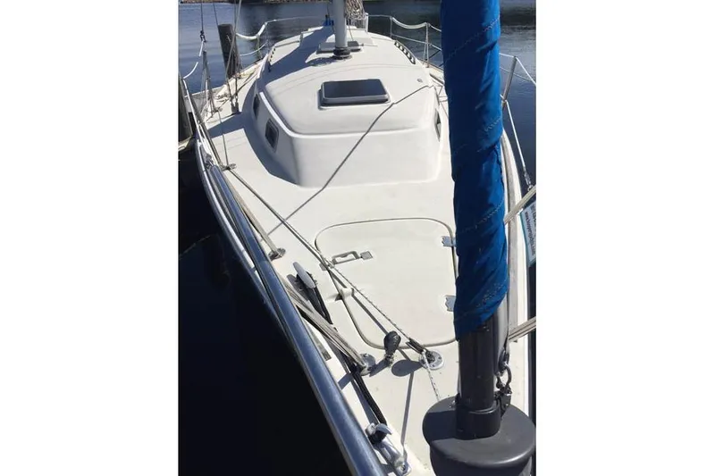 Slide: The Image of 1983 Pearson 303 sailboat deck with blue sail cover, docked in calm waters. - 3