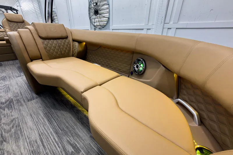Slide: The Image of Luxurious tan seating on 2026 Godfrey Sanpan 25' Tritoon boat, featuring quilted design and built-in speakers. - 14