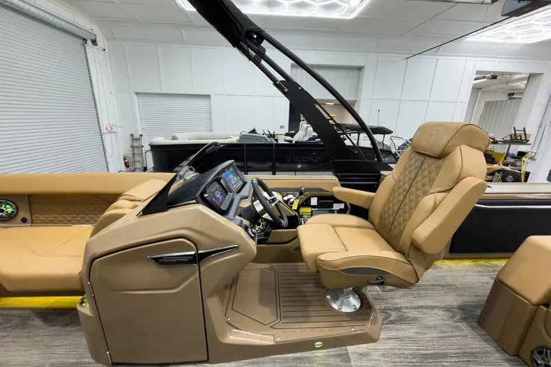 Slide: The Image of Luxurious 2026 Godfrey Sanpan 25' Tritoon with plush captain's chair and modern dashboard. - 21