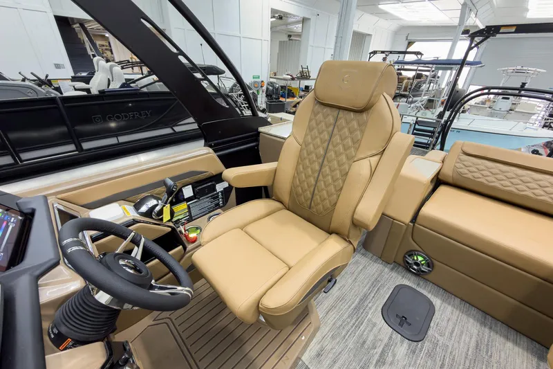 Slide: The Image of 2026 Godfrey Sanpan 25' Tritoon interior with luxurious captain's chair and steering console. - 22