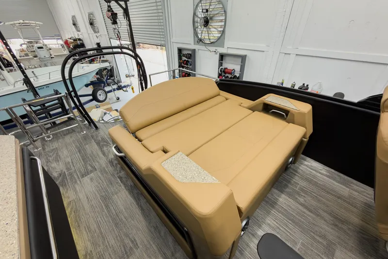 Slide: The Image of 2026 Godfrey Sanpan 25' Tritoon with tan flip lounge seating in a showroom. - 40