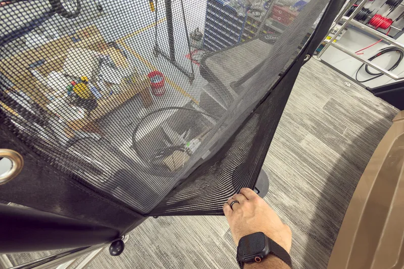 Slide: The Image of Hand adjusting mesh cover on 2026 Godfrey Sanpan 25' Tritoon boat interior. - 47