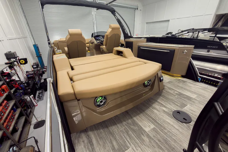 Slide: The Image of 2026 Godfrey Sanpan 25' Tritoon with flip lounge, co-captain seats, in a garage setting. - 49