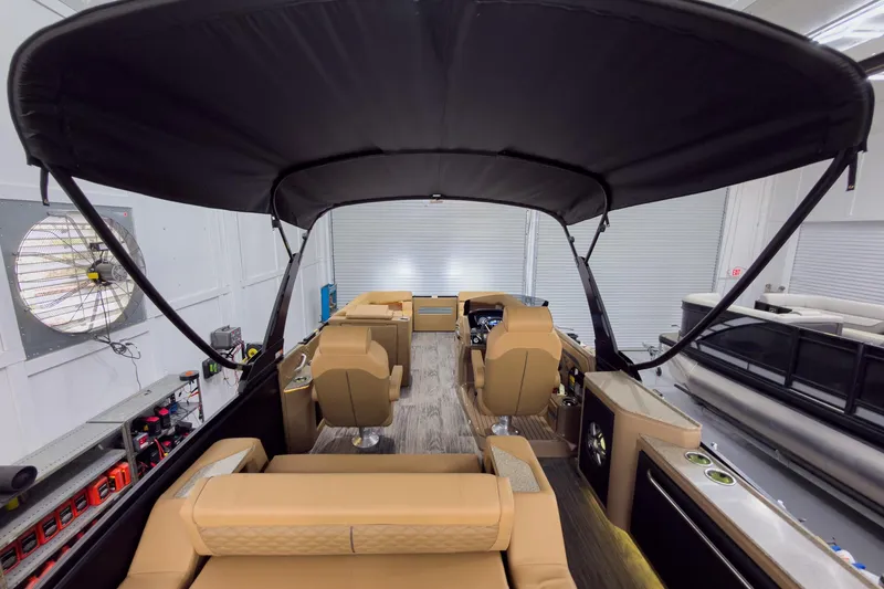Slide: The Image of 2026 Godfrey Sanpan 25' Tritoon interior with tan seating and black canopy. - 57