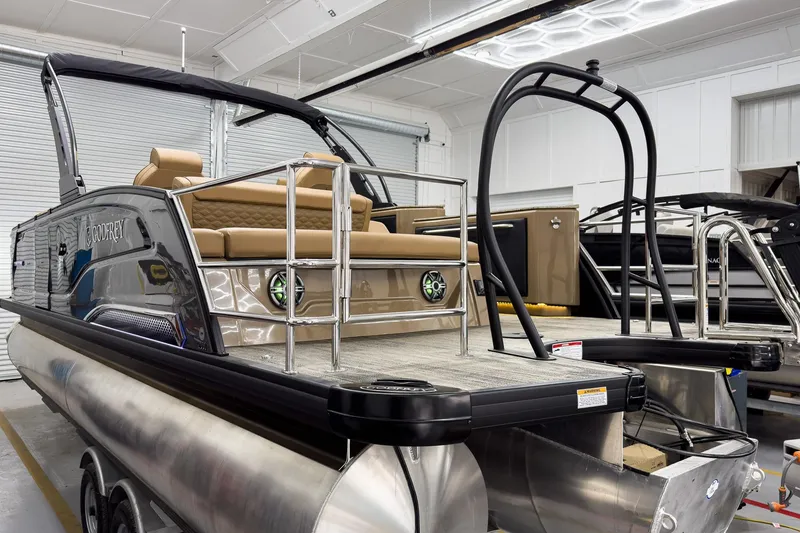 Slide: The Image of 2026 Godfrey Sanpan 25' Tritoon with flip lounge, showcased in a showroom setting. - 8